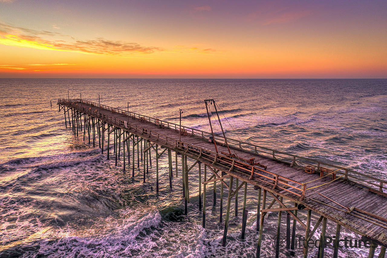 Carolina Beach pier running toward the horizon under an orange sky